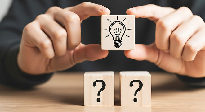 Person holding wooden cube with lightbulb drawing above two cubes with question marks hand