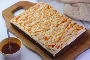 Chocolate sheet cake with a thick layer of buttercream frosting, drizzled with caramel cream sauce