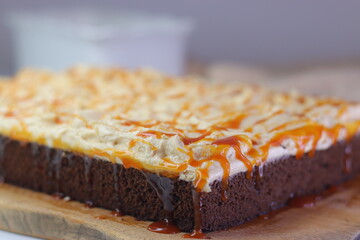 Chocolate sheet cake with a thick layer of buttercream frosting, drizzled with caramel cream sauce
