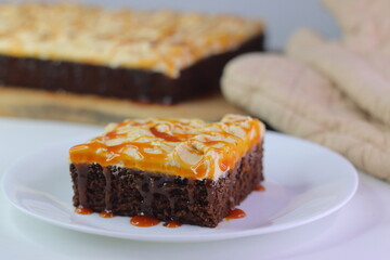 Moist chocolate cake slice topped with buttercream frosting and drizzled with caramel cream sauce.