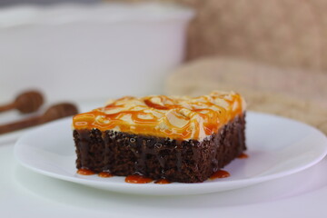 Moist chocolate cake slice topped with buttercream frosting and drizzled with caramel cream sauce.
