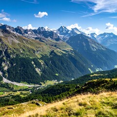 Obraz premium A vibrant, expansive mountain vista under a bright blue sky with fluffy clouds. Green slopes descend, leading to a valley, snowy peaks in the distance