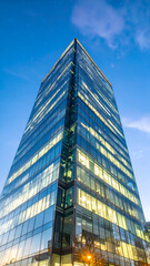 Modern Glass Skyscraper Towering Against a Blue Sky at Dusk.