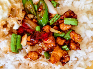 Close-up of Thai basil chicken stir-fry with rice, green beans, and peppers in savory sauce