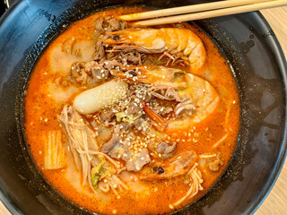 Shrimp and beef in spicy red broth with rice cake and mushrooms