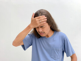 long haired man holding his head because he has a headache