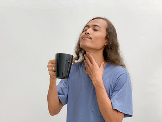 long haired man after drinking with his hands holding the cup and neck