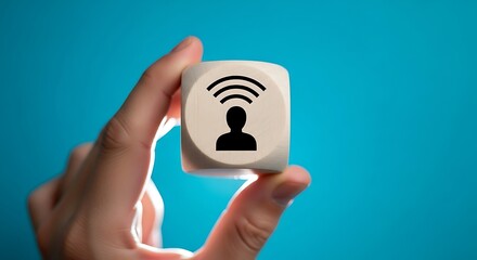 Hand holding wooden cube with person and wifi symbol on blue background