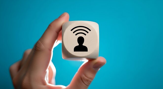 Hand holding wooden cube with person and wifi symbol on blue background