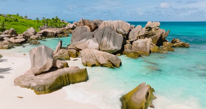 Granite boulders scattered on a pristine white sand beach with turquoise water. Seychelles, La Digue. Anse Cocos.