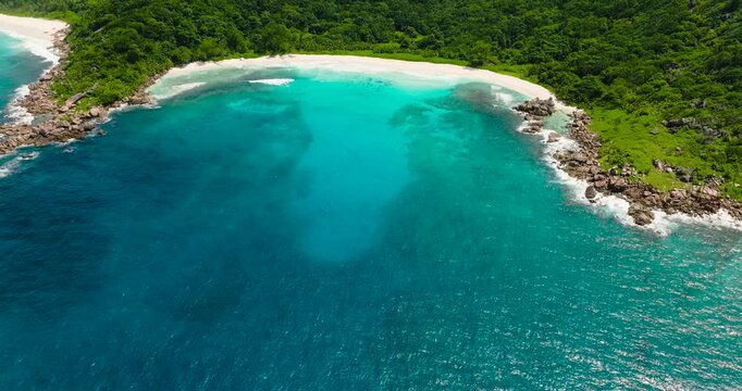 An inviting bay with crystal clear turquoise waters surrounded by rocky shores and lush vegetation. Anse Cocos. Seychelles, La Digue.