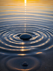 A pebble dropped into still water, creating ripples at sunset.