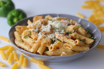 Creamy rigatoni in white sauce topped with grated cheese, herbs, and red pepper flakes