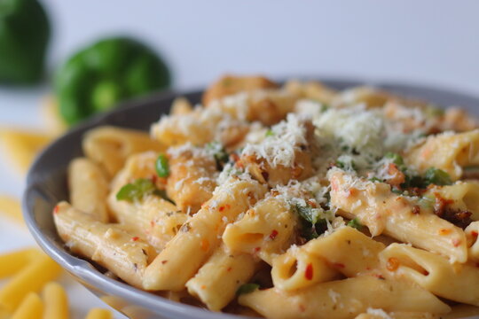 Creamy rigatoni in white sauce topped with grated cheese, herbs, and red pepper flakes