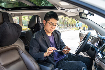 Man sitting in car using digital tablet for work or leisure