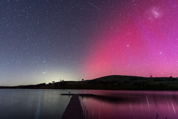 Aurora Australis display lights up the sky in pinks over the dam