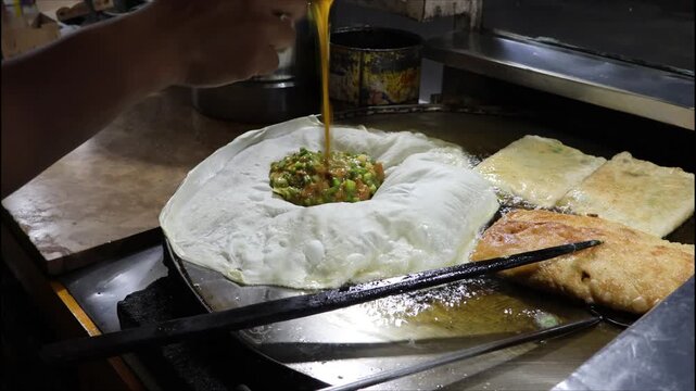 Martabak telur is a popular dish in Indonesia. It uses bread dough to wrap the filling, which is meat mixed with spices. It is fried until golden brown and fragrant, ready to be served with other side