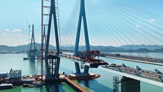 Aerial shot of a massive cable-stayed bridge under construction, an impressive feat of engineering and infrastructure over the sea. Famous Xiangshan Port Cross-Sea Bridge is located in Ningbo, China.