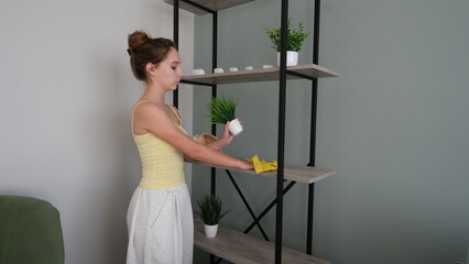 A girl wipes dust on a shelf