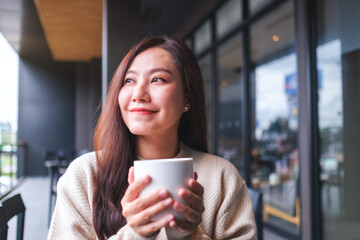 Portrait image of a woman holding a cup of hot coffee