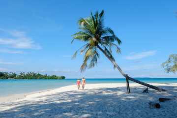 Couples stroll along the pristine beaches of Koh Kood Island in Thailand on a sunny day