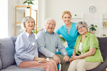 Positive group of happy senior people and caring kind smiling nurse, geriatric medicine caretaker providing old help, support during medical visit in retirement home, female doctor caregiving service