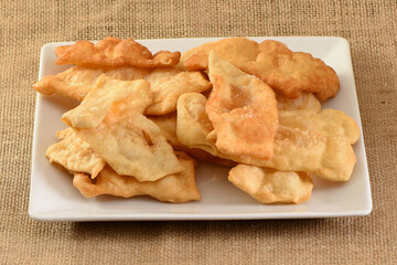 Homemade puff pastry on a square white plate. Traditional preparation of fried puff pastry. Christmas tradition