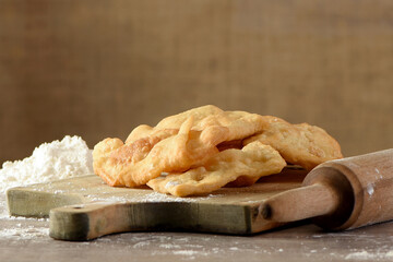 Homemade puff pastry on a floured wooden board with a rolling pin. Traditional preparation of fried puff pastry. (Copy space)