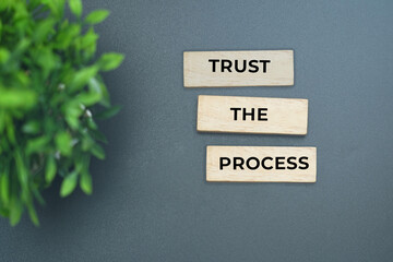 Trust the process message on wooden blocks against minimal background