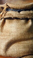Close-up view of a heavily textured, brown burlap sack with tied top and blue plastic ties