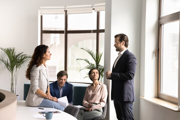 Engaged multiethnic workers gather in office hall for casual conversation