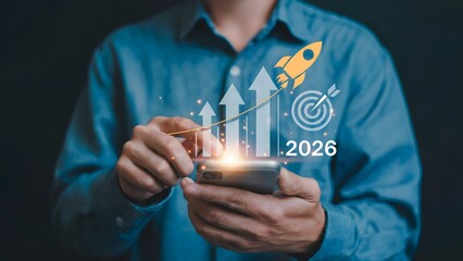 A person in a blue shirt using a smartphone and touching a glowing virtual interface with a rocket icon upward arrows and a 2026 target symbol