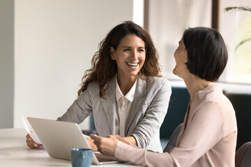 Young businesswoman celebrate successful work result with mature female colleague