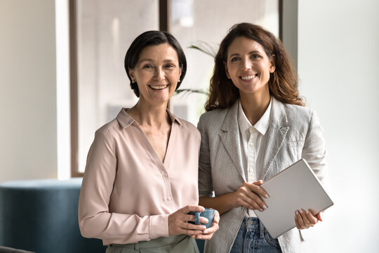 Smiling diverse businesswomen colleagues standing in office looking at camera