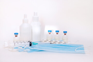 A still life of medical syringes and medication vials. Disposable syringes, medical masks, and fever pills. Supplies for injections and virus protection. 