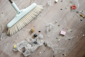 A broom sweeping dust and debris from a wooden floor, showcasing dirt and small objects. Ideal for cleaning and home maintenance themes.