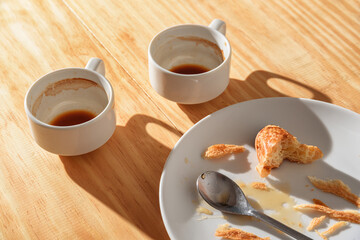 Empty espresso cups and croissant crumbs on white plate