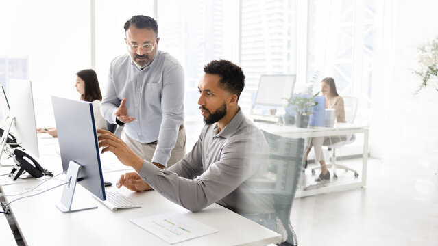 Serious busy diverse young and senior coworkers discussing Internet content