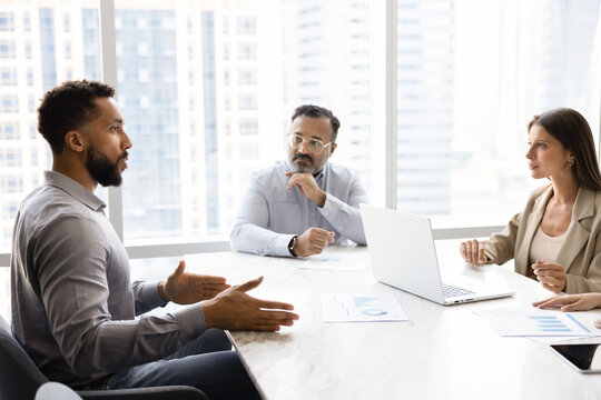 Diverse team of different aged coworkers talking at negotiation table