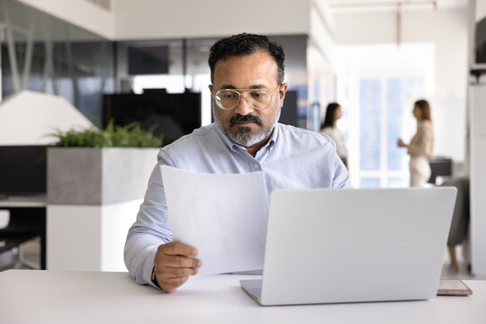 Serious elder mature Indian business leader man reading legal document - Powered by Adobe