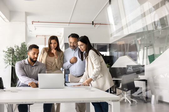 Multiethnic team of business professionals meeting at laptop together