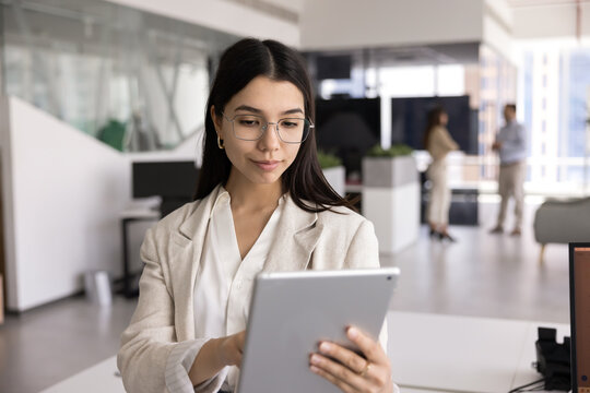 Busy business professional woman in glasses typing on tablet PC