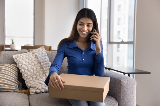 Positive young consumer woman holding postal cardboard box at home - Powered by Adobe