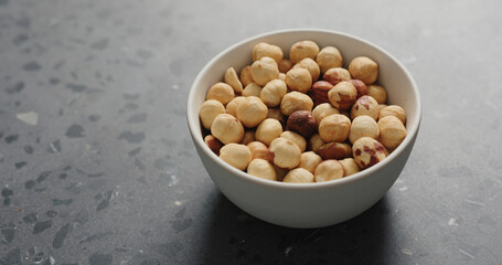 roasted hazelnuts in white bowl on terrazzo countertop