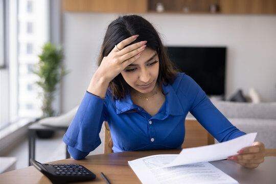 Serious young Indian woman reading legal document