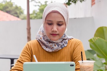 An Asian Muslim businesswoman working in an outdoor cafe