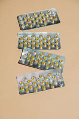 Blister packs with capsules for treating bloating are neatly arranged on a beige background