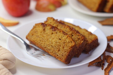 Slices of moist apple cinnamon bread on a white plate with a fork