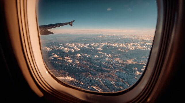 Vibrant aerial view from an airplane window showcasing fluffy clouds and distant mountains during a clear afternoon flight over scenic landscapes