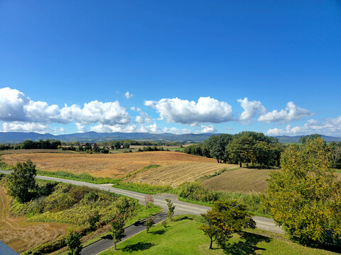Fototapeta The image captures a serene vista of rolling hills, verdant fields, and a majestic mountain peak, all bathed in sunlight
